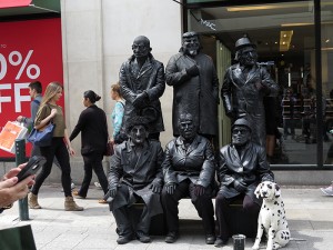 Men dressed in black posing as statues