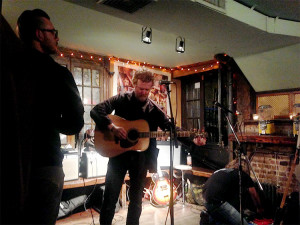 Glen tuning his guitar at Scratcher